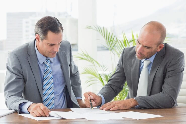 Two men discussing documents at table.