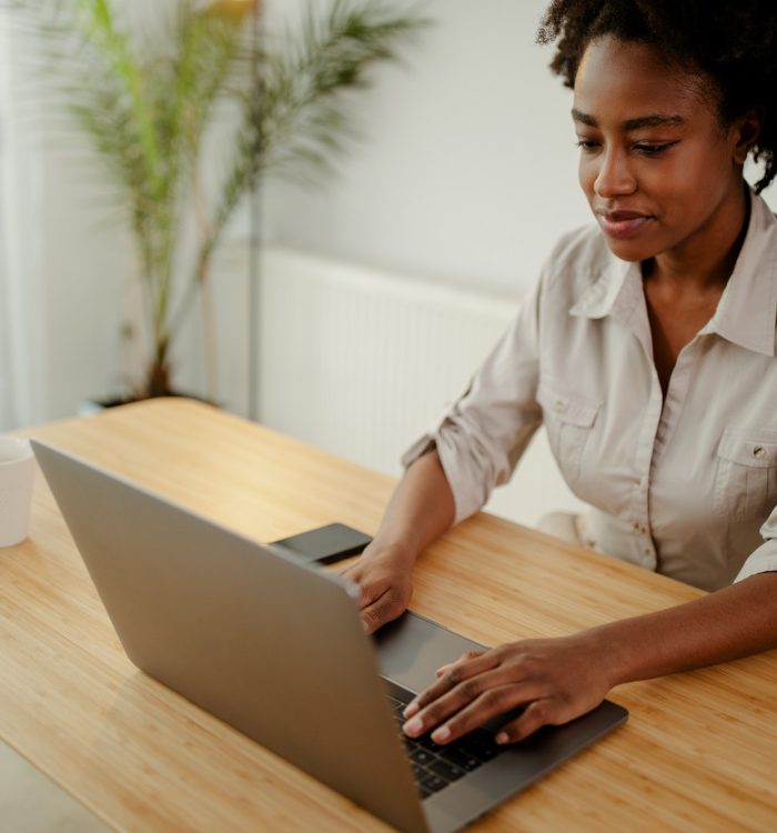 Concentrated afro american copywriter updating software on laptop computer in office.
