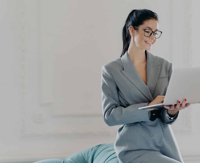 Happy female entrepreneur types on laptop computer, works in modern workspace in business center, Contract Review Lawyer, Travel Solicitors