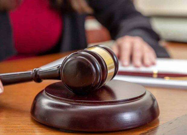 Law courtroom, Judge Bench. Woman sitting, auction gavel and notepad on wooden table, close up, Investment Fraud Lawyer, Discrimination Lawyer