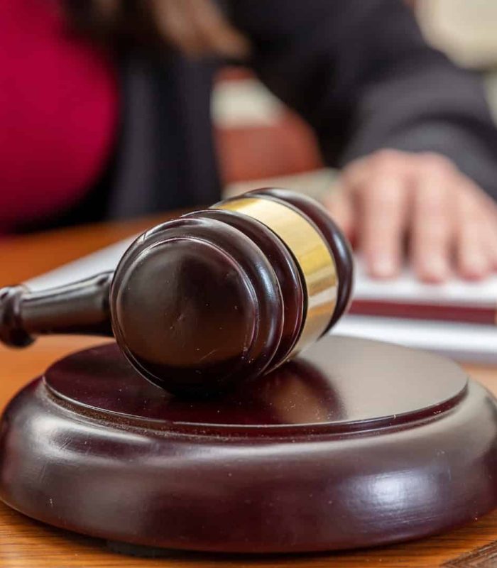 Law courtroom, Judge Bench. Woman sitting, auction gavel and notepad on wooden table, close up, Investment Fraud Lawyer, Discrimination Lawyer
