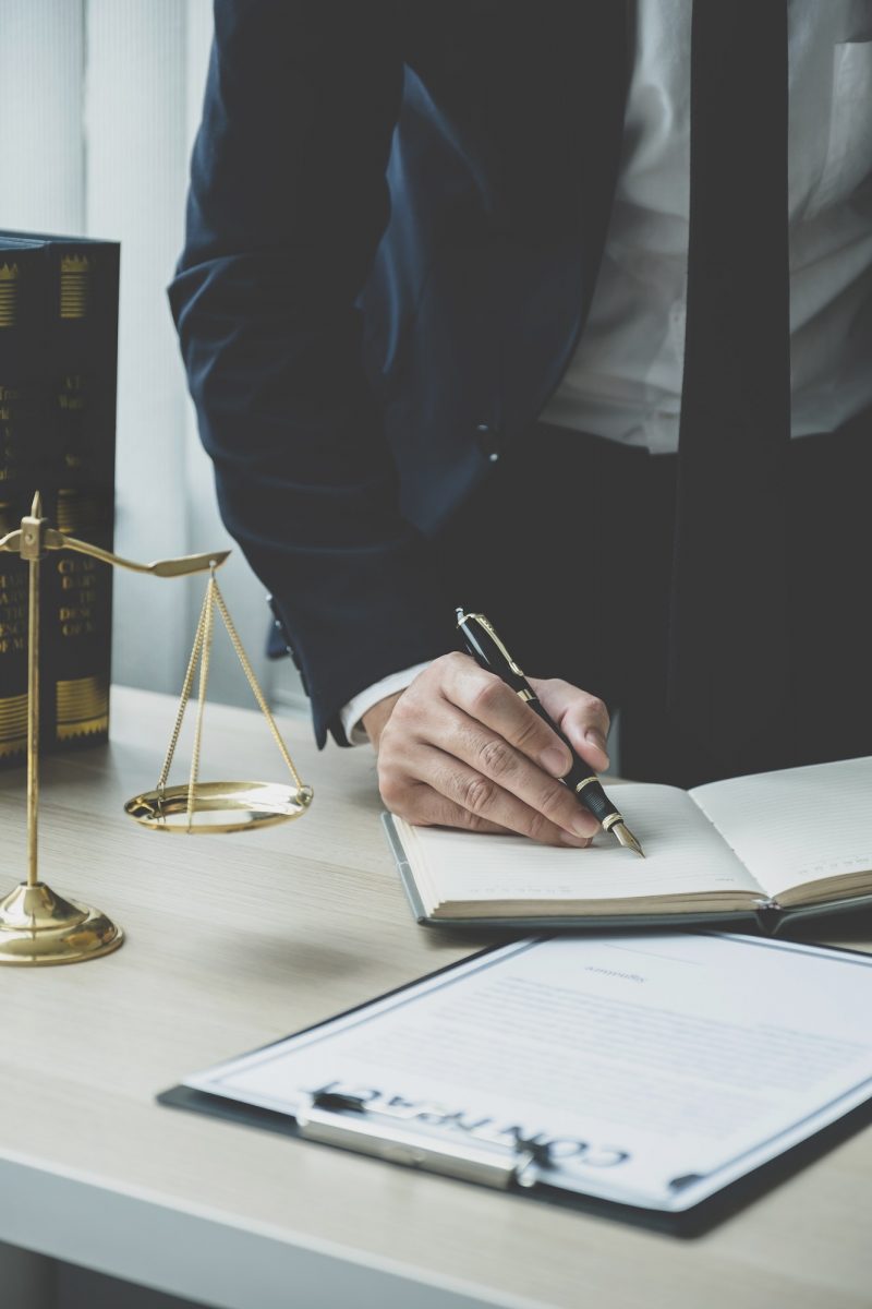 Lawyer hand holding pen and providing legal consult business dispute service at the office