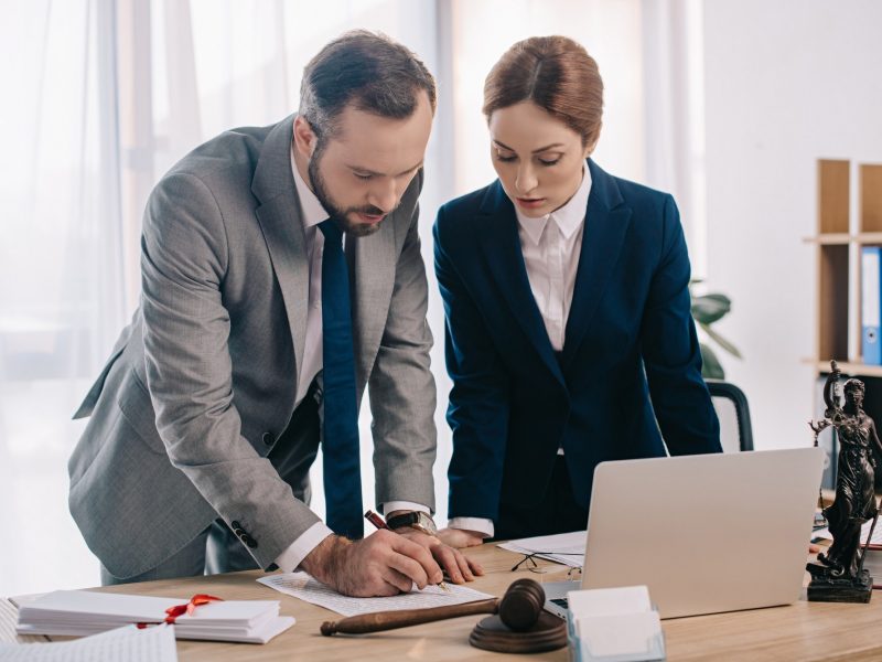 lawyers-in-suits-working-together-on-project-at-workplace-with-gavel-and-laptop-in-office.jpg