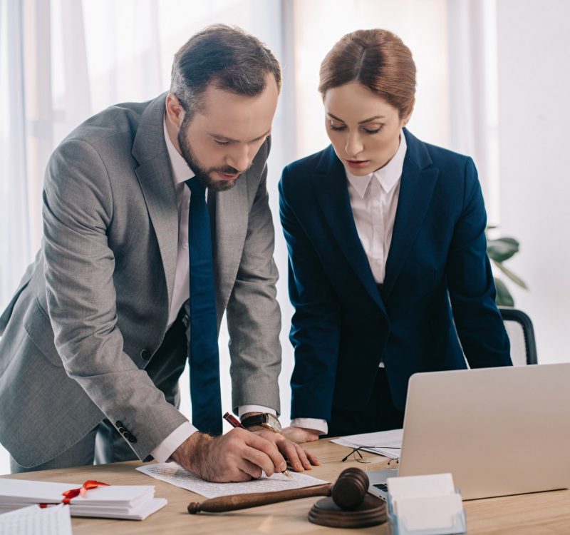 lawyers-in-suits-working-together-on-project-at-workplace-with-gavel-and-laptop-in-office.jpg
