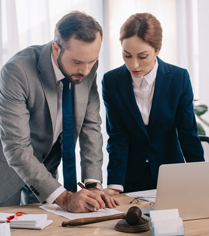 lawyers-in-suits-working-together-on-project-at-workplace-with-gavel-and-laptop-in-office.jpg