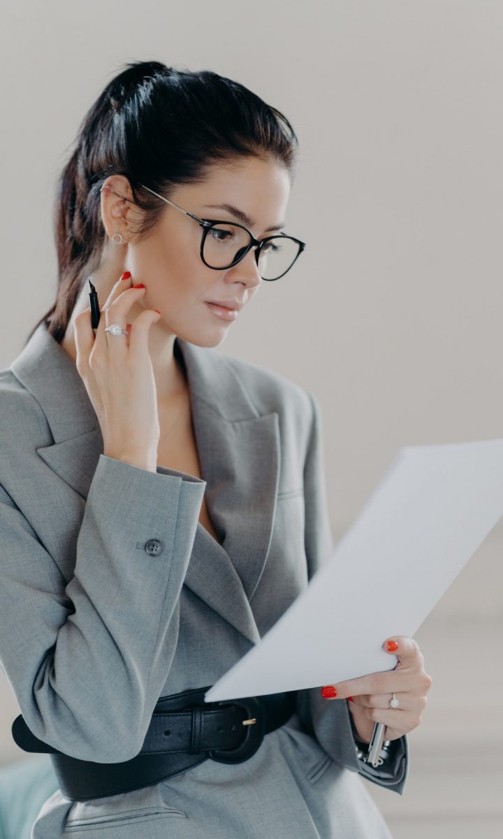 Successful female executive manager looks through paper documents, analyzes data