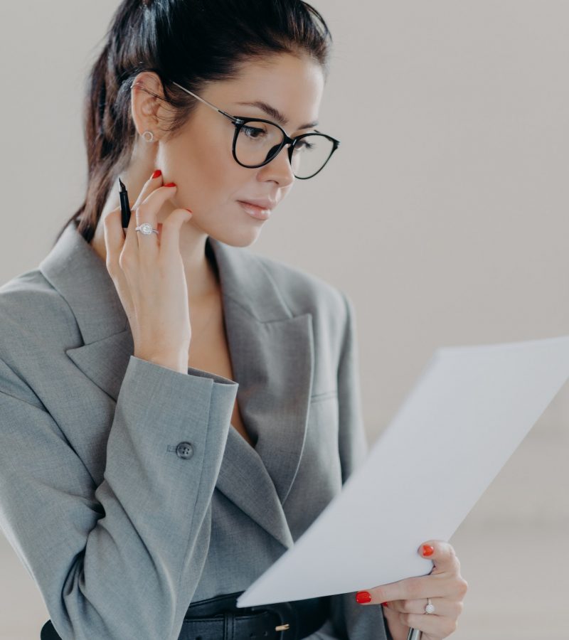 Successful female executive manager looks through paper documents, analyzes data