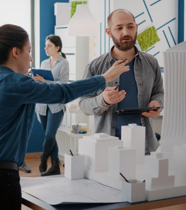 team-coworkers-analyzing-maquette-building-model-plan-construction-tablet-architectural-people-working-together-designing-urban-strategy-real-estate-development_482257-38839