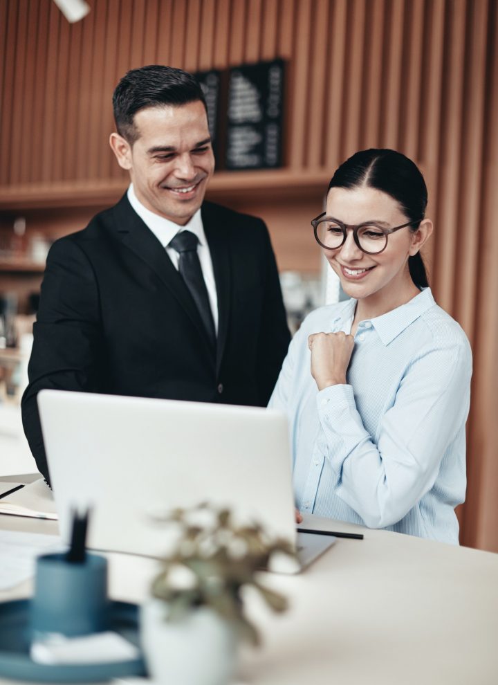two-smiling-businesspeople-using-a-laptop-together-in-an-office.jpg