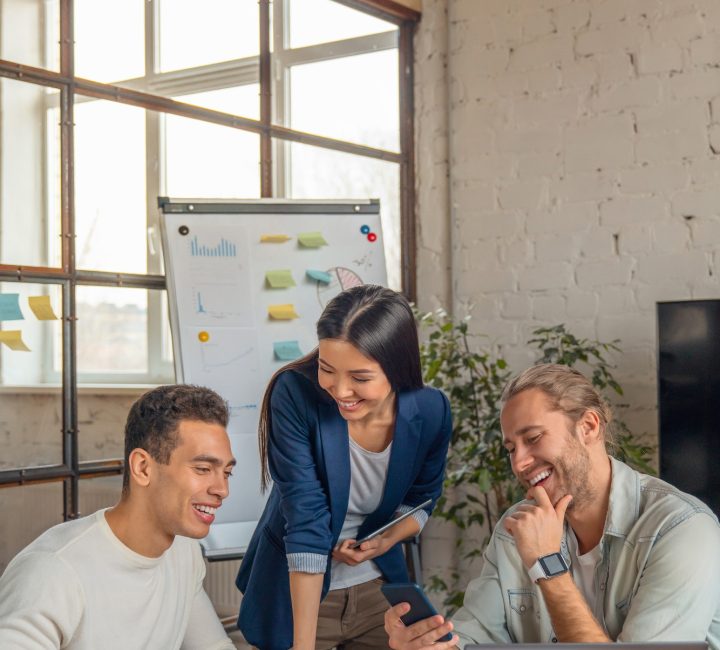 Vertical shot of multiracial business people with laptop and smartphone having meeting in office.